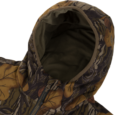 Close-up of a Waterfowl Drake X Ducks Unlimited LST BMF Jacket with Primaloft, featuring a camouflage pattern of brown leaves and dark branches.