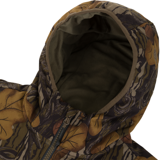 Close-up of a Waterfowl Drake X Ducks Unlimited LST BMF Jacket with Primaloft, featuring a camouflage pattern of brown leaves and dark branches.