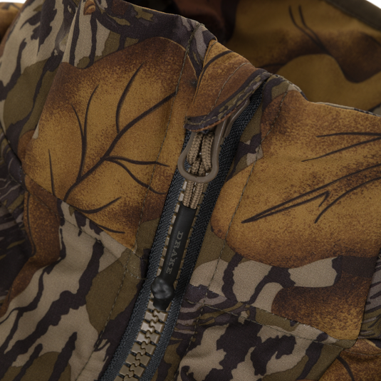 Close-up of a camouflage-patterned Drake X Ducks Unlimited LST BMF Vest with Primaloft, showing a zipper closure with a branded pull tab.