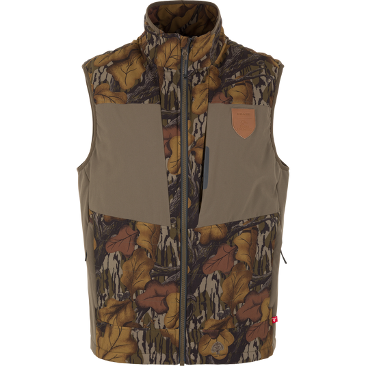 Zip-up Drake X Ducks Unlimited LST BMF Vest with Primaloft in Mossy Oak Fall Foliage, featuring a leaf-print camouflage pattern with solid olive panels on the chest and a leather logo patch on the upper left.