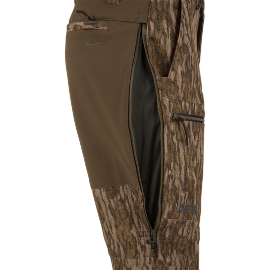 MST CommandXT Softshell Pant close-up showing camo fabric, side-zippered vent with black mesh, thigh pocket, and logo near hem for mobility and protection.