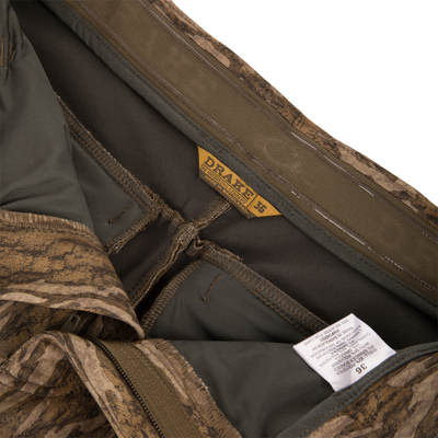 Inside waistband of MST CommandXT Softshell Pant showing DRAKE label, size 36, partially unzipped fly, care tag, and interior seams.