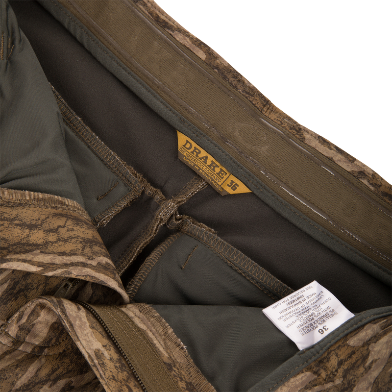 Inside waistband of MST CommandXT Softshell Pant showing DRAKE label, size 36, partially unzipped fly, care tag, and interior seams.