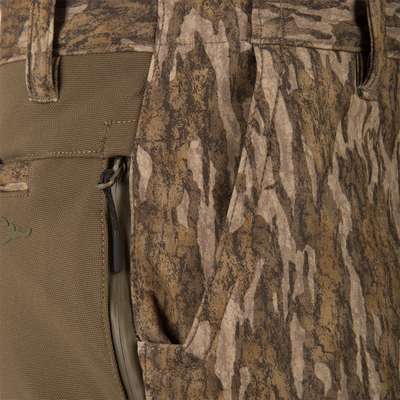 Close-up of MST Youth CommandXT Softshell Pant camouflage pants featuring a zippered pocket, a solid-colored panel, and a stretch waistband.