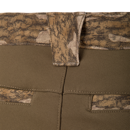 Close-up of olive green MST Youth CommandXT Softshell Pant featuring a camouflage-patterned waistband and back pockets with a belt loop at the center.