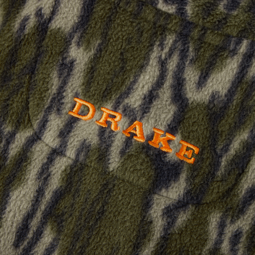 Close-up of Drake Camp Fleece Limited Edition Snap Pullover, showcasing camouflage-patterned fleece with bright orange DRAKE embroidery and featuring a Magnattach pocket.