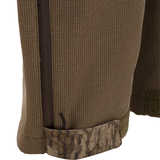 Close-up of LST CommandXT Bib's hem with micro-grid fabric, camo Velcro strap, and zipper, highlighting durability and functionality for extreme hunting conditions.