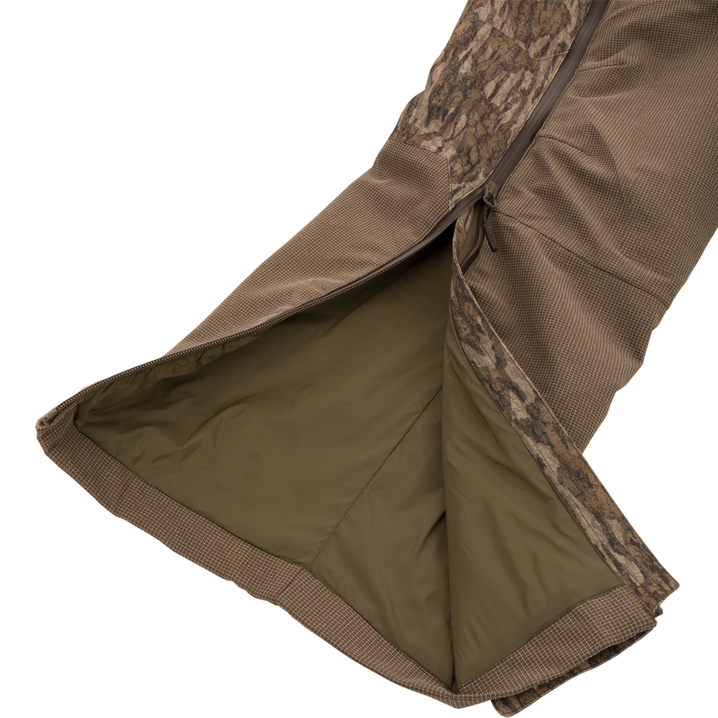 LST CommandXT Bib with Primaloft shown with camo shell, revealing olive lining and side zipper, highlighting its warmth and durability for extreme hunting conditions.