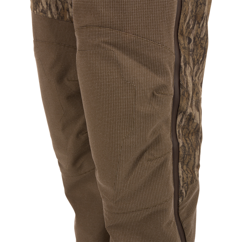 Close-up of the LST CommandXT Bib with Primaloft showing a camo side-panel, brown fabric with grid pattern, and vertical zippered seam for durability and warmth.