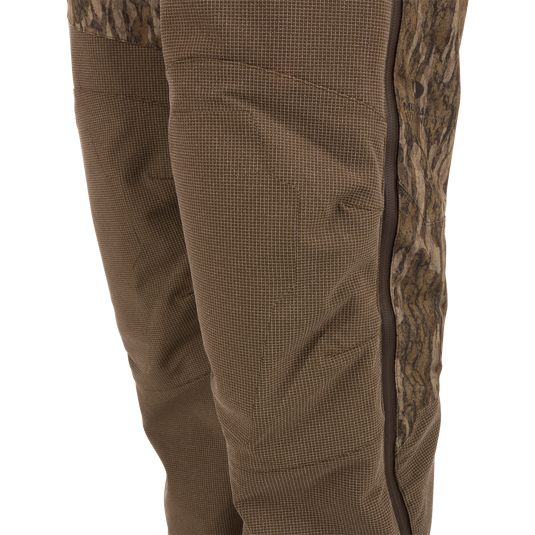 Close-up of the LST CommandXT Bib with Primaloft showing a camo side-panel, brown fabric with grid pattern, and vertical zippered seam for durability and warmth.