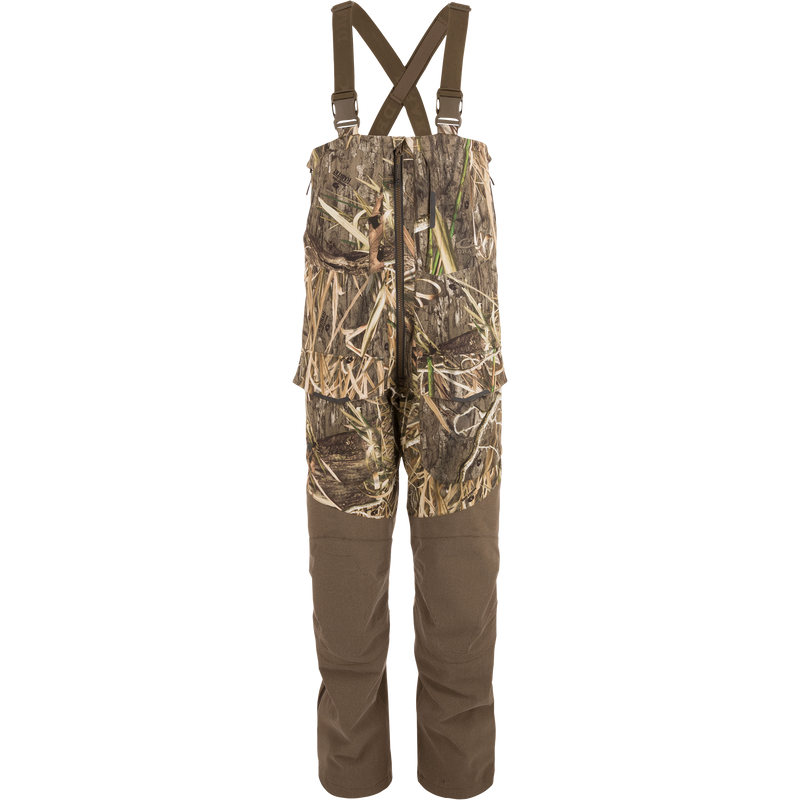 LST CommandXT Bib with Primaloft: Camouflage bib-overalls featuring adjustable suspenders, reinforced panels, waterproof zippers, cargo pockets, and articulated knees, designed for extreme hunting conditions.
