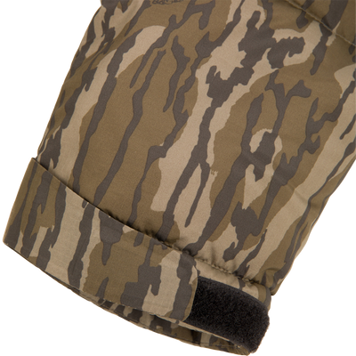 Close-up of a padded, camouflage-print winter glove with a Velcro wrist strap, part of the BMF Down Jacket collection by Drake Waterfowl, designed for demanding hunting conditions.