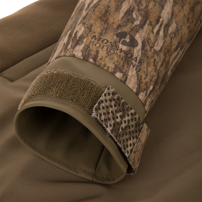 LST BMF Eqwader Half Zip Jacket's cuff features Mossy Oak Bottomland camo, Velcro adjustment strap, and rubberized grip nubs for secure fit.