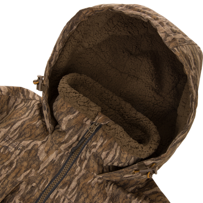 LST BMF Eqwader Half Zip Jacket with Primaloft, featuring camo-pattern, sherpa-lined hood, front zipper, and hood-adjustment toggles, designed for warmth and functionality in outdoor conditions.