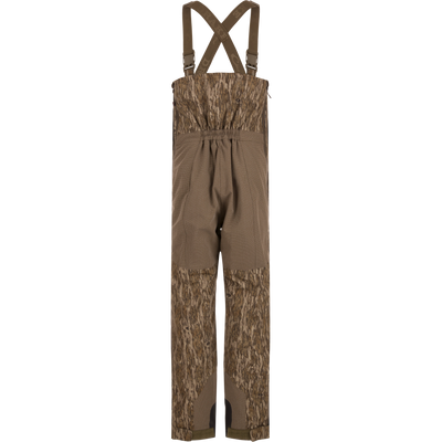 LST BMF Pit Bib with Primaloft: Camouflage bib pants featuring wood-grain camo, reinforced knee/seat panels, adjustable suspenders, and full-length zippers, ideal for rugged hunting conditions.