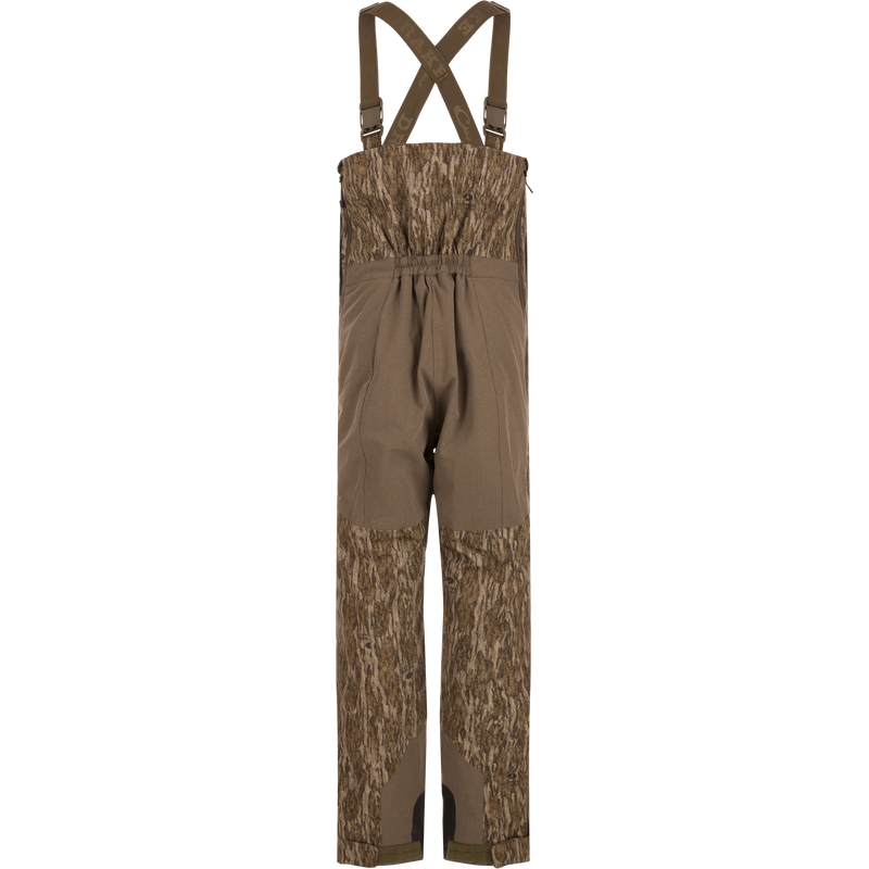 LST BMF Pit Bib with Primaloft: Camouflage bib pants featuring wood-grain camo, reinforced knee/seat panels, adjustable suspenders, and full-length zippers, ideal for rugged hunting conditions.