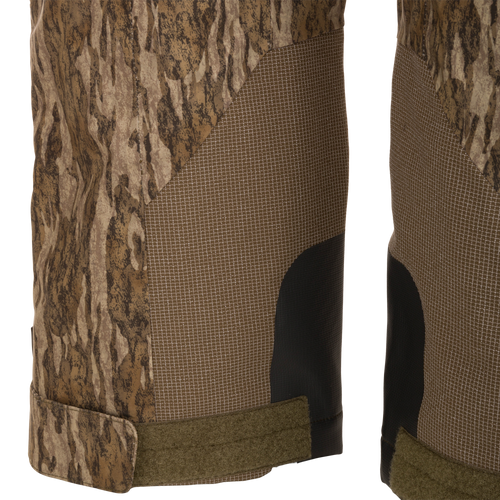 Close-up of LST BMF Pit Bib ankle cuffs, showcasing camo panels, grid-pattern reinforcements, abrasion-resistant patches, and adjustable straps for secure boot fit.