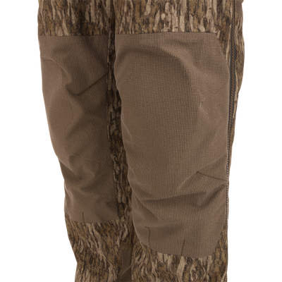 Close-up of LST BMF Pit Bib highlighting camo design, reinforced knee panels, and side zipper, showcasing durable construction and weather protection for rugged hunting conditions.
