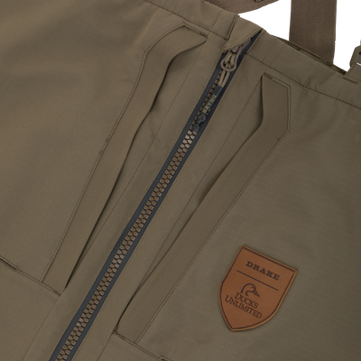 Olive green Drake X Ducks Unlimited LST BMF Pit Bib with Primaloft chest waders featuring a front zipper and a leather patch with a duck logo and Drake and Ducks Unlimited text.