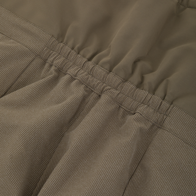 Close-up of olive green Drake X Ducks Unlimited LST BMF Pit Bib with Primaloft hunting pants featuring an elasticized waistband and a grid-patterned lower section.