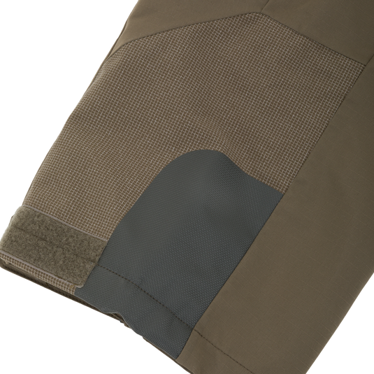 Close-up of olive green Drake X Ducks Unlimited LST BMF Pit Bib with Primaloft outdoor pants featuring a reinforced dark patch on the knee and a velcro closure at the leg opening.