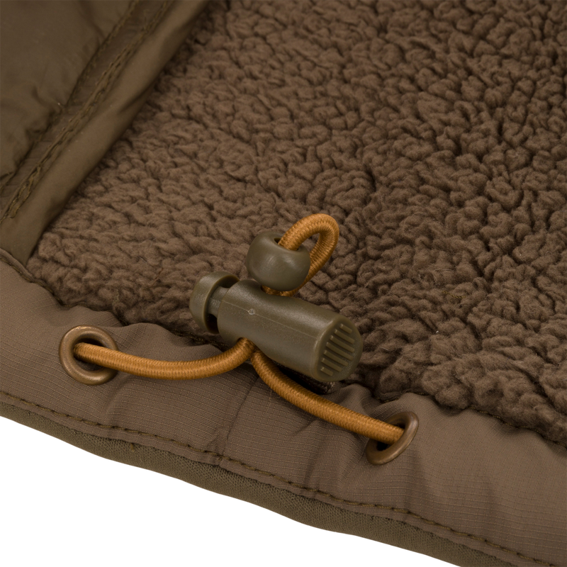 Close-up of LST BMF 3-in-1 Pit Jacket's chocolate-brown sherpa fleece lining with olive-green binding, tan drawcord, and cord-lock toggle, highlighting its rugged construction.