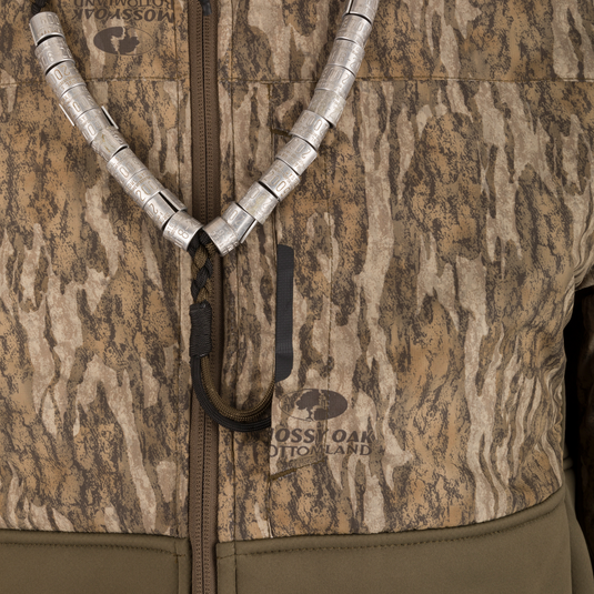 Close-up of the LST BMF 3-in-1 Pit Jacket with Primaloft, showcasing camouflage pattern, braided lanyard, and metal duck calls, emphasizing rugged outdoor versatility and protection.