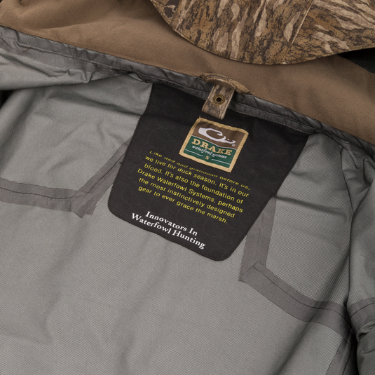 Inside view of the LST BMF 3-in-1 Pit Jacket with Primaloft, showcasing branding, durable materials, and camo-patterned hood edge for versatile hunting protection.