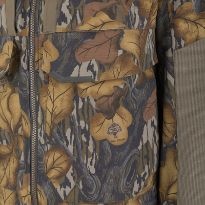 Close-up of a Drake X Ducks Unlimited LST BMF 3-in-1 Pit Jacket with Primaloft in a brown leaf camouflage pattern, featuring a front zipper and a chest pocket with a flap.