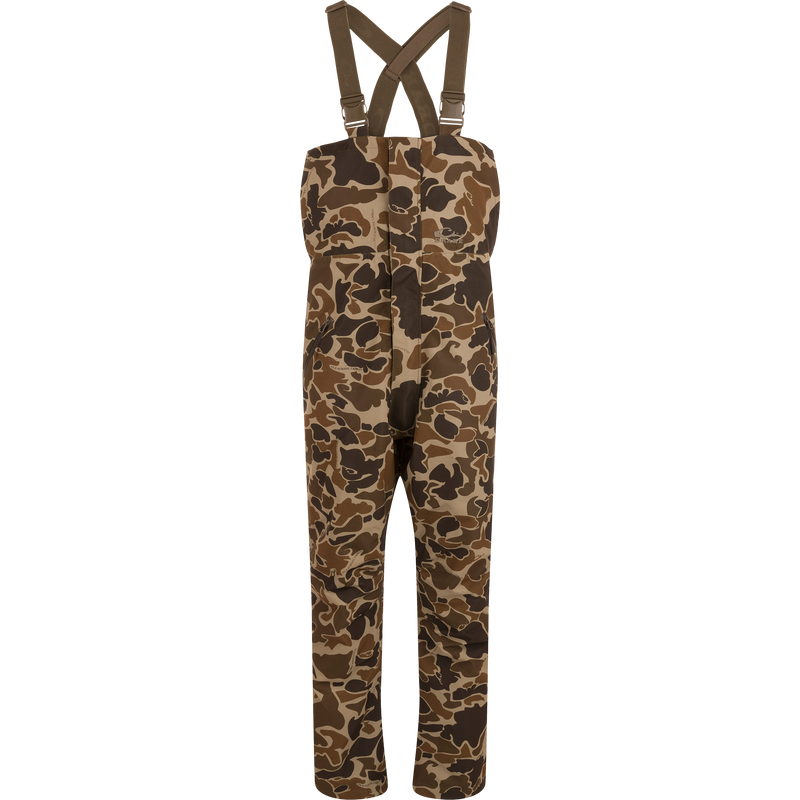 LST Hardline Insulated Bib with camo pattern, adjustable suspenders, and storm-resistant zippers, designed for warmth and mobility in harsh outdoor conditions.
