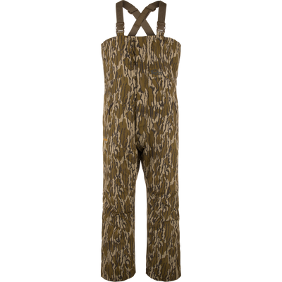 LST Hardline Insulated Bib: Camouflage-pattern, waterproof chest-high waders with adjustable straps, handwarmer pockets, and articulated knees for enhanced mobility in harsh hunting or fishing conditions.
