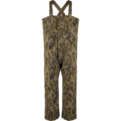 LST Hardline Insulated Bib featuring a tree-bark camouflage pattern, adjustable shoulder straps, and articulated knees for mobility, designed for warmth in harsh hunting conditions.