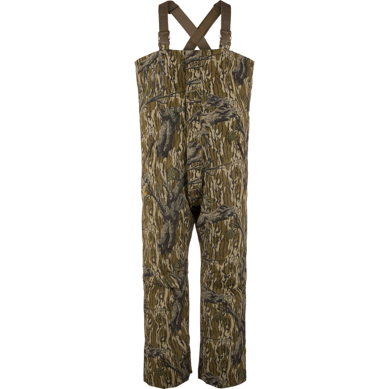 LST Hardline Insulated Bib featuring a tree-bark camouflage pattern, adjustable shoulder straps, and articulated knees for mobility, designed for warmth in harsh hunting conditions.