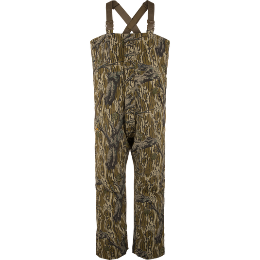 LST Hardline Insulated Bib featuring a tree-bark camouflage pattern, adjustable shoulder straps, and articulated knees for mobility, designed for warmth in harsh hunting conditions.