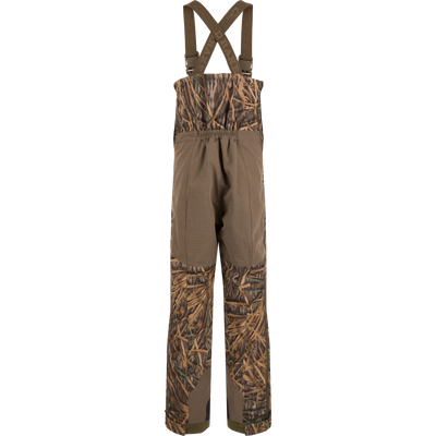 BMF Uninsulated Pit Bib with marsh-grass camo and solid brown panels, featuring adjustable suspenders, reinforced TPU zones, and Velcro cuffs for durable hunting performance.