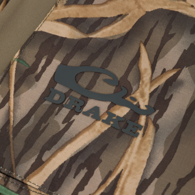 Close-up of BMF Uninsulated Pit Bib's camo fabric with black logo, showcasing durable stitching and premium materials designed for harsh hunting conditions.