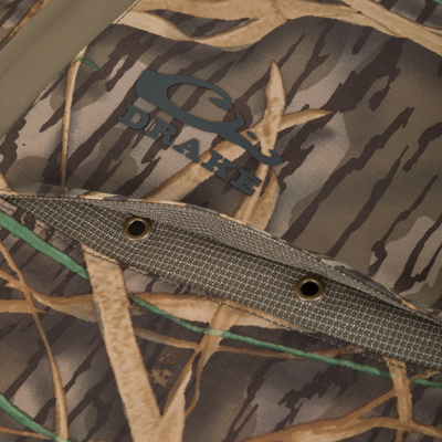 Close-up of BMF Uninsulated Pit Bib's camouflage fabric with Drake logo patch, showcasing durable construction with metal grommets and stitched detailing for outdoor performance.