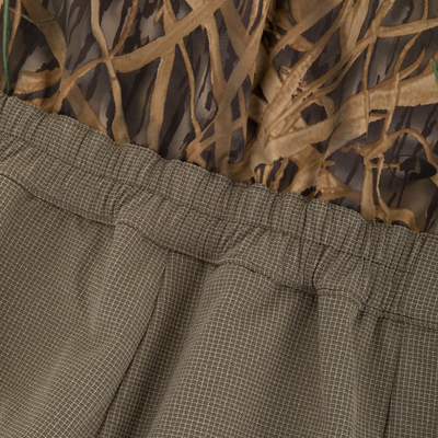 Close-up of BMF Uninsulated Pit Bib featuring brown camouflage print and olive-green waistband with elastic edge, designed for durability and protection in harsh conditions.