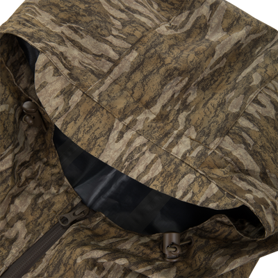 RTL - El Poncho detail shot showing a desert/tiger-stripe camo hood, draw-cord toggles, and seam-taped interior, highlighting its waterproof features for versatile outdoor use.