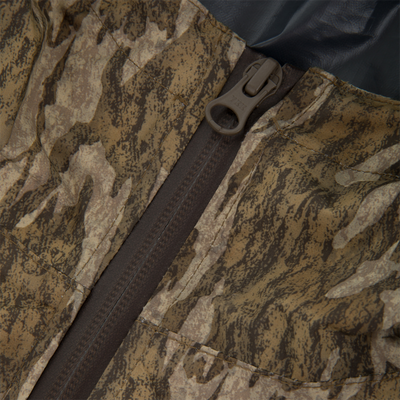 Close-up of RTL - El Poncho's camouflage fabric with stitched panels and brown YKK zipper, showcasing its waterproof, durable design for versatile hunting protection.