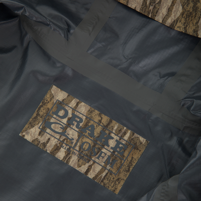 Close-up of RTL - El Poncho's taped black waterproof seams with a camo-patterned label, showcasing durable construction for outdoor protection.