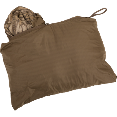 MST Synthetic Down Pack Vest shown packed in brown bag with visible camouflage cloth inside.