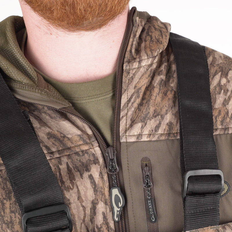 A close-up of a man wearing the LST Insulated Bib 2.0, featuring fleece-lined hand warmer pockets and full-length zippers on each side for easy removal.
