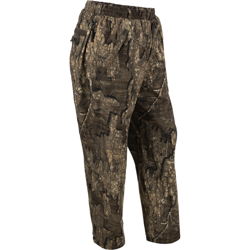 A pair of camouflage pants for hunters, designed for total waterproof protection. Cut generously to wear over base layers, jeans, or other pants. Features elastic waist, zippered pockets, and ankle-to-knee zippers for easy on/off. From Drake Waterfowl.