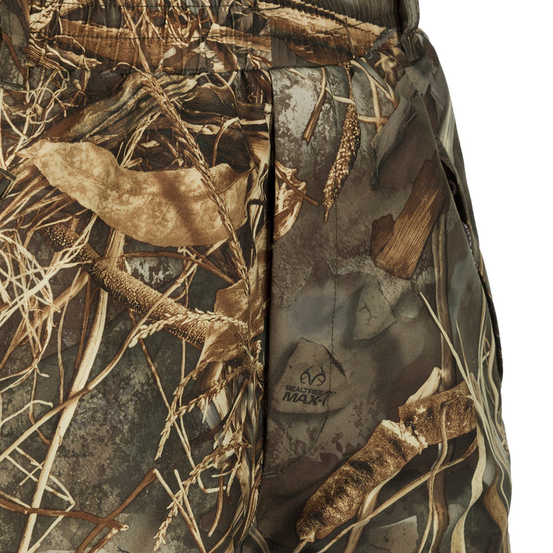 A close-up of the EST Waterproof Over Pant, a camouflage shorts with a pattern resembling a spotted animal. Designed for hunters, these pants provide total waterproof protection and can be worn over base layers or jeans. Perfectly pairs with the EST Heat-Escape Full Zip or 1/4 for lightweight rain gear.