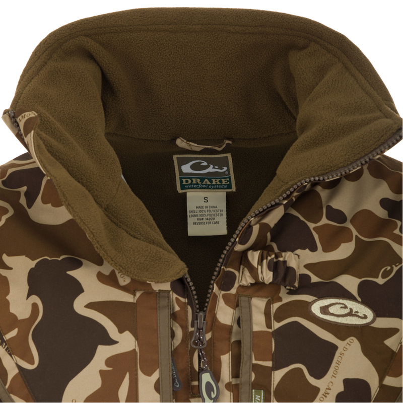 Close-up of the MST Waterproof Fleece-Lined Quarter Zip Jacket with Drake label, showcasing camouflage shell, olive fleece lining, and central zipper.