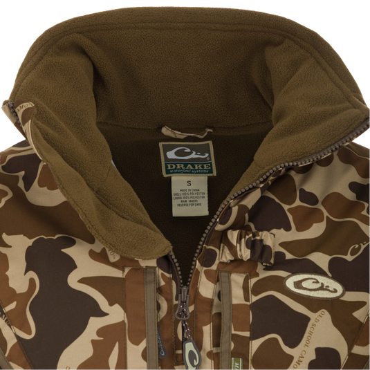 Close-up of the MST Waterproof Fleece-Lined Quarter Zip Jacket with Drake label, showcasing camouflage shell, olive fleece lining, and central zipper.