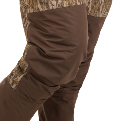 Person wearing Women’s Insulated Guardian Elite Vanguard Breathable Waders, featuring camouflage design, reinforced seams, and insulated liner for warmth and durability in cold hunting conditions.
