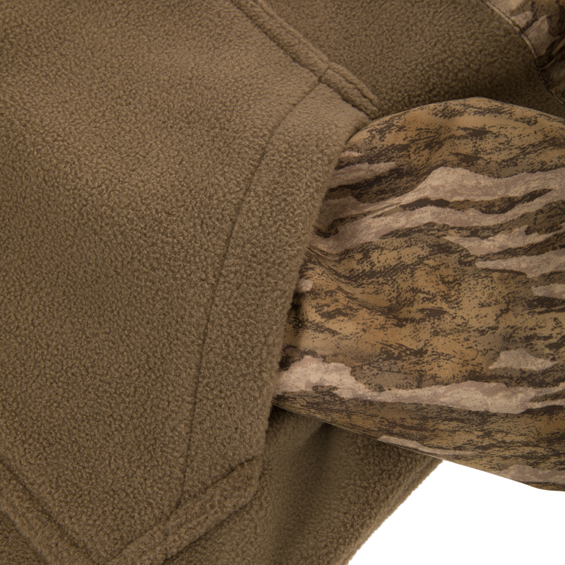 Close-up of MST Youth Eqwader Quarter Zip Jacket, showcasing olive fleece and camo-patterned fabric, highlighting the dual-zone technology for optimal comfort and performance in waterfowl hunting.