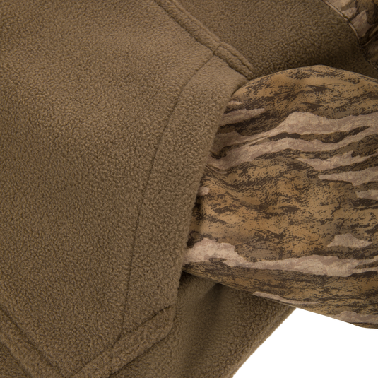 Close-up of MST Youth Eqwader Quarter Zip Jacket, showcasing olive fleece and camo-patterned fabric, highlighting the dual-zone technology for optimal comfort and performance in waterfowl hunting.
